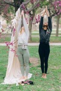 2 woman in the nature are doing yoga